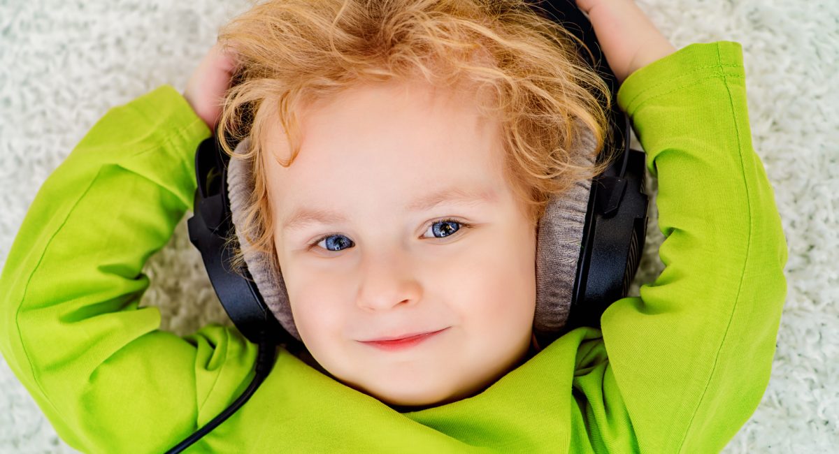 Little 3 year old boy listening to music in headphones.